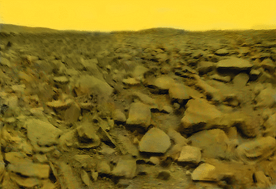 Spacecraft image of a lifeless, dry, rocky planetary surface, under a yellow sky.