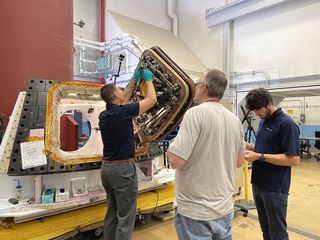 jeremy hansen standing at an open spacecraft door while two people stand nearby him