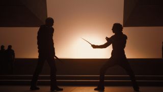 Image from the sci-fi movie Dune. Silhouettes of two figures about to duel each other with short swords.