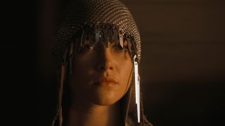 Image from the sci-fi movie Dune. Close up of a woman's face who is wearing a chainmail hood with metal tassels.