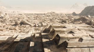 Image from the sci-fi movie Dune. The city of Arrakeen as seen from above. There are lots short, minimalistic buildings all covered in sand.