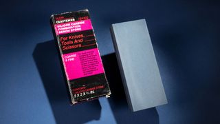 closeup of a rectangular gray whetstone and a pink and black paperback book