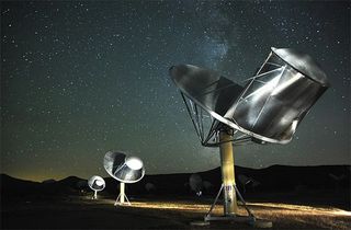 Two telescopes with dishes at the top looking up at the sky.