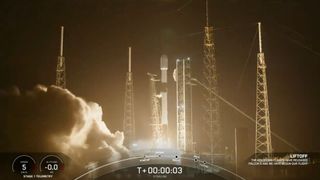 a black-and-white spacex falcon 9 rocket launches into a night sky.