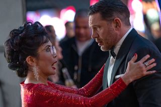 A woman in a sparkly red dress embraces a man in a tuxedo