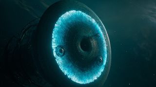 A large cylindrical spaceship floating in space, it's end glowing bright blue.