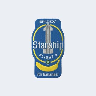 a blue spaceflight mission patch, showing a silver spacecraft above a yellow banana and the phrase 