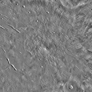 a black-and-white photograph of a dry landscape dotted with craters and fissures, as seen from overhead