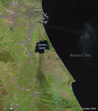 Aerial view from a high altitude, with green land on the left, and the Balearic Sea on the right.