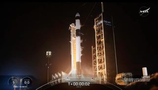 a black-and-white spacex falcon 9 rocket launches into a night sky.