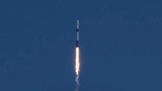 a white rocket lifts off under a sunny sky