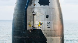 closeup of part of a silver spacecraft, which features a drawing of a cartoon banana holding a banana.