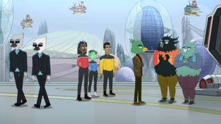 cartoon characters in bright, primary colors stand inside a room filled with lights and buttons on a futuristic spaceship