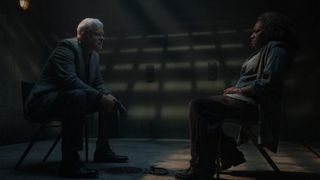 A man sits opposite a woman in an interrogation room